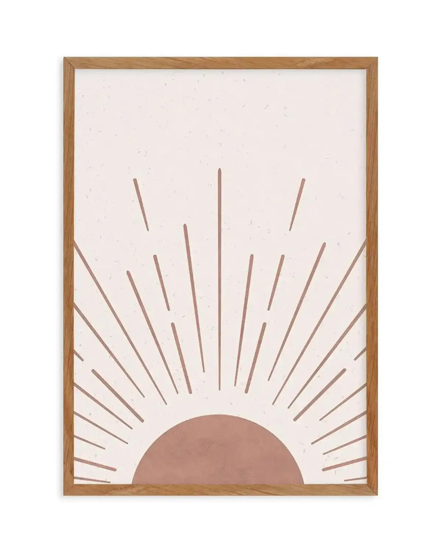 Art print featuring a minimalist illustration of a rising sun in a warm, dusty rose hue against a textured off-white background, displayed in a natural oak frame with white border. The sun is depicted as a half-circle at the bottom, with radiating lines of varying lengths extending upwards.