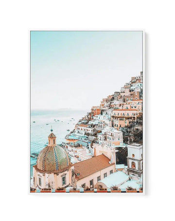 Framed canvas of Positano, Italy cliffside in peach and white with teal church dome and blue sea, white frame