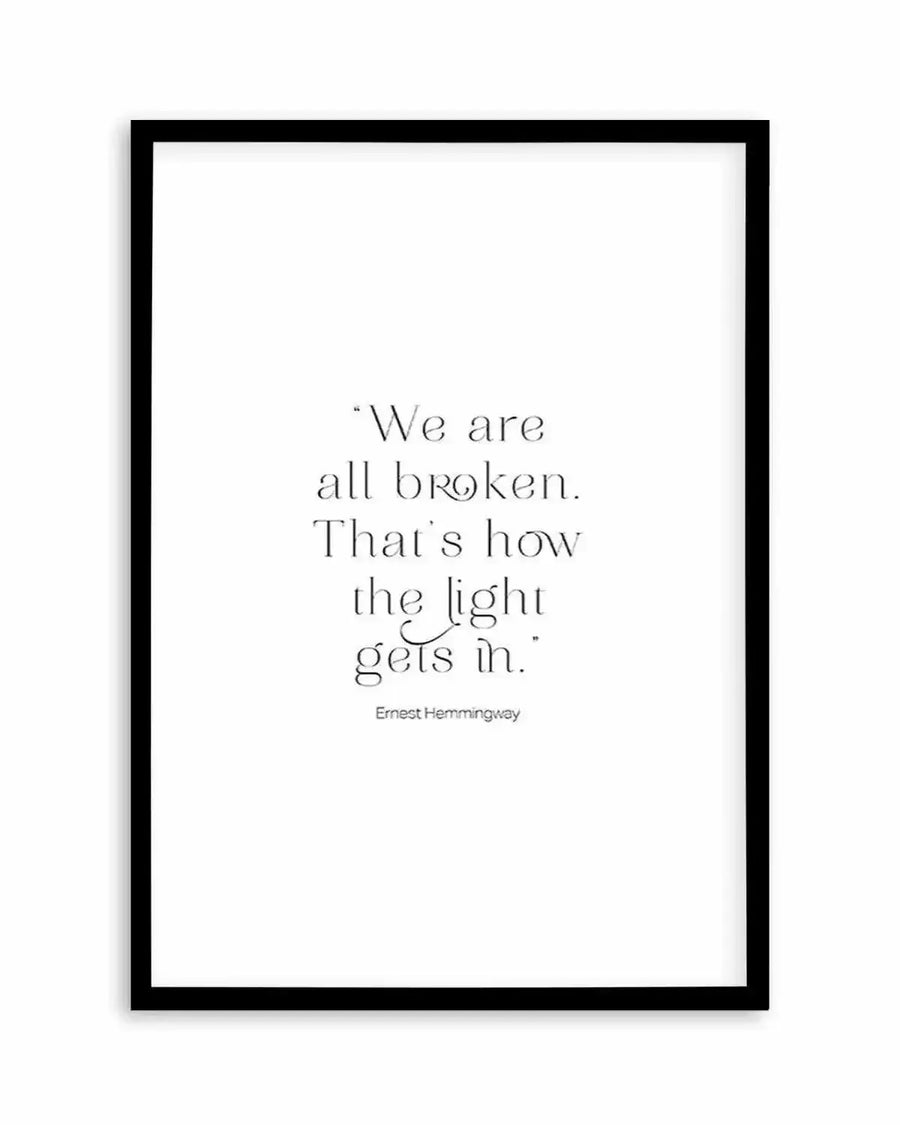 Art print featuring a quote by Ernest Hemingway in black serif font on a plain white background, displayed in a black frame with a white border. The quote reads: "We are all broken. That's how the light gets in."