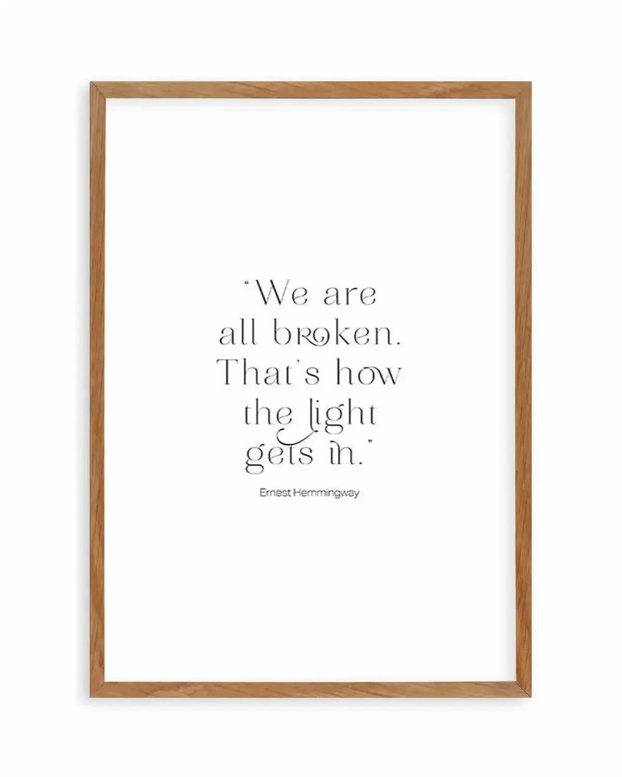 Art print featuring the quote "We are all broken. That's how the light gets in." by Ernest Hemingway in black serif font on a white background, displayed in a natural oak frame with white border.