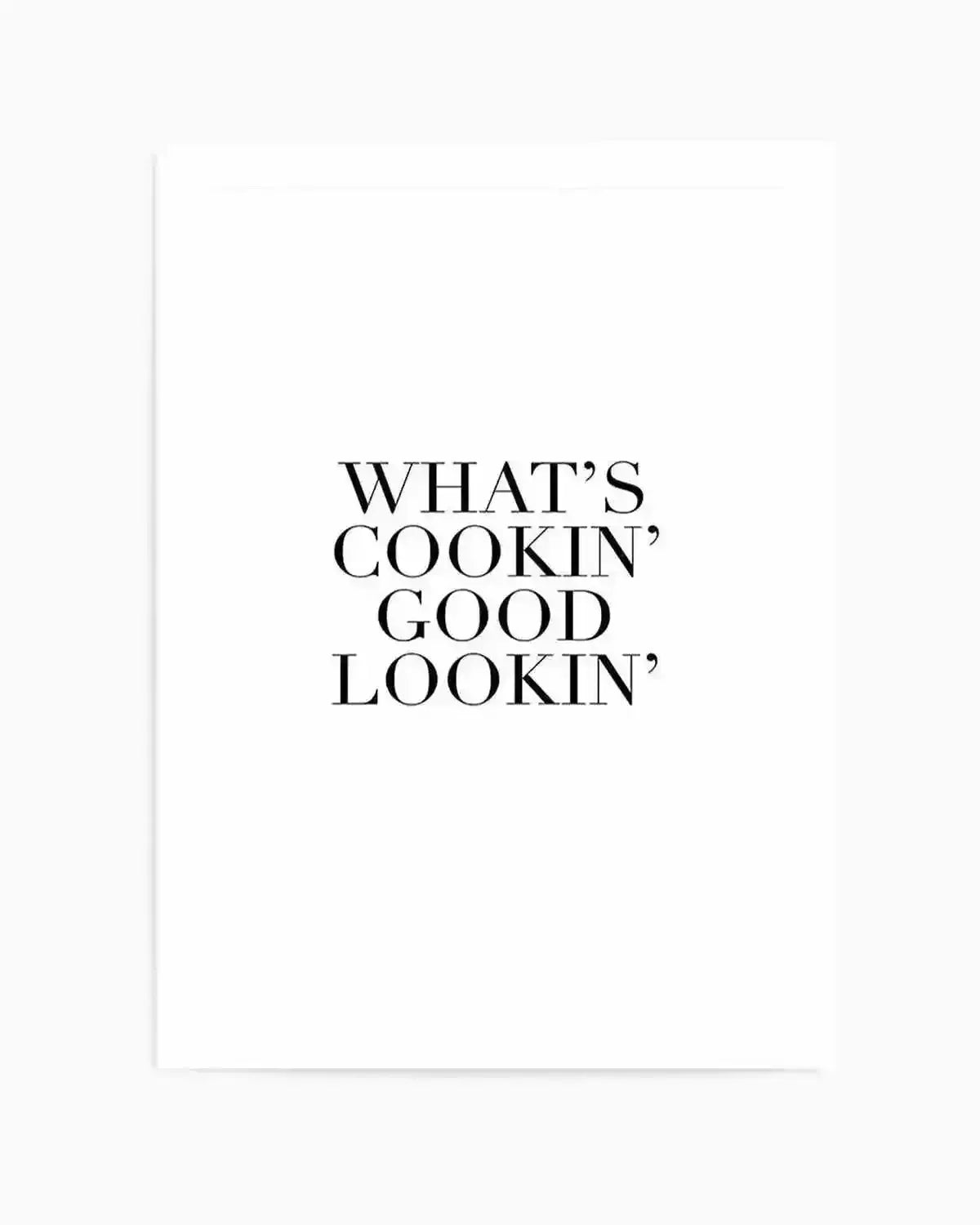 Art print featuring black serif typography centered on a white background. The text reads "WHAT'S COOKIN' GOOD LOOKIN'" arranged in four lines. The print has a clean, minimalist design with classic letterpress-style lettering in a tall, elegant serif font. The artwork is matted with a white border and displayed against a light gray background.