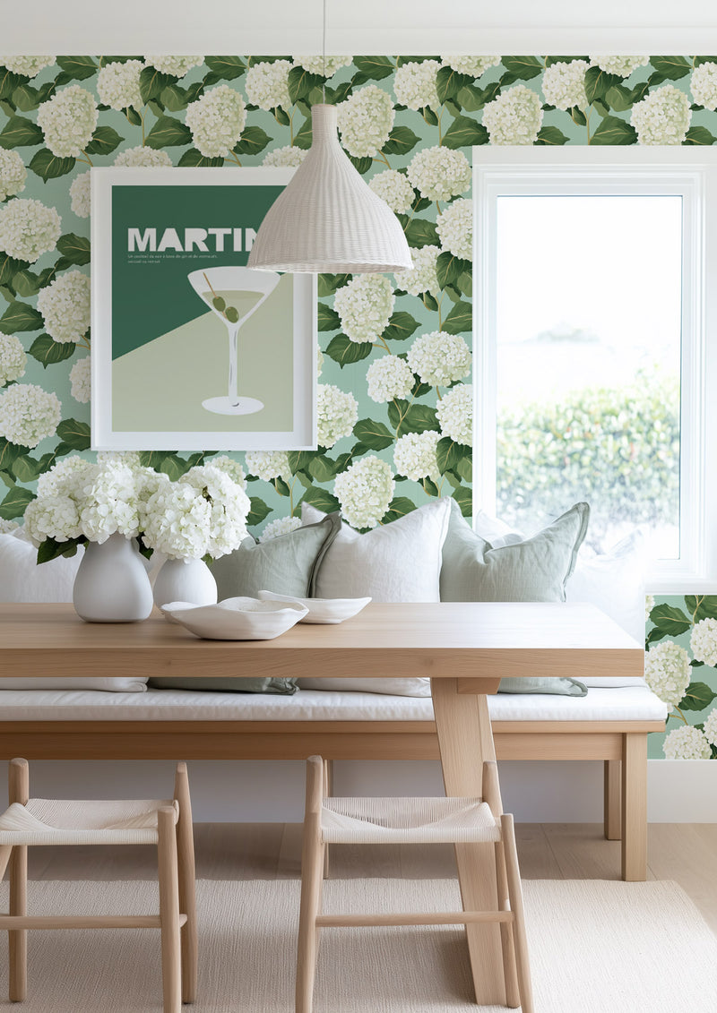 Dining room featuring mint green hydrangea wallpaper with martini artwork and a rustic wooden table.