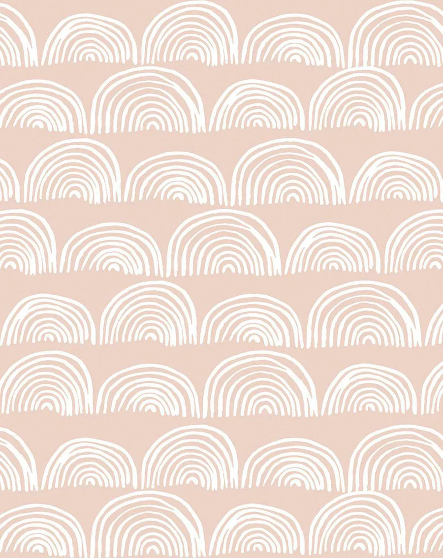 Peel and stick wallpaper featuring a repeating pattern of hand-drawn rainbows in white on a soft, muted blush pink background. The rainbows are composed of multiple concentric arcs with a loose, organic, and slightly irregular hand-drawn quality.