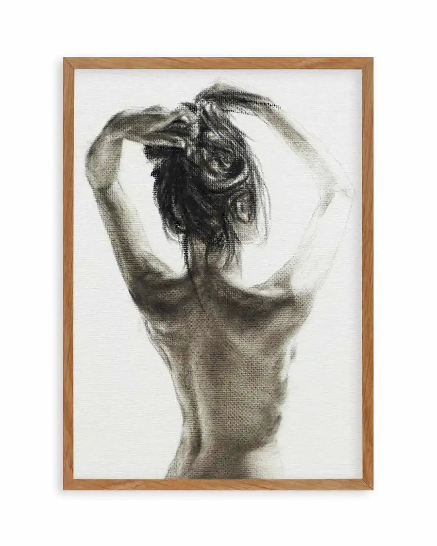 Charcoal art print featuring the back of a woman with her arms raised, hands in her hair, on a white background, printed on fine art paper and displayed in a natural oak frame with white border.