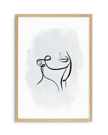 Framed art print featuring a minimalist line drawing of an abstract face in profile, rendered with continuous black ink lines on a white background. A soft, diffused periwinkle blue watercolor wash creates a subtle rounded background shape behind the figure. The drawing shows simplified facial features with closed or downturned eyes and a curved smile. Natural wood frame with white border. Vertical composition on white paper.