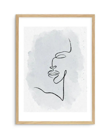 Abstract face line drawing in black ink on white paper with soft gray watercolor wash background, displayed in natural wood frame with white border. Minimalist continuous line illustration of a profile featuring curved eye, nose, lips, and chin. Organic, contemplative aesthetic with subtle texture from watercolor medium.