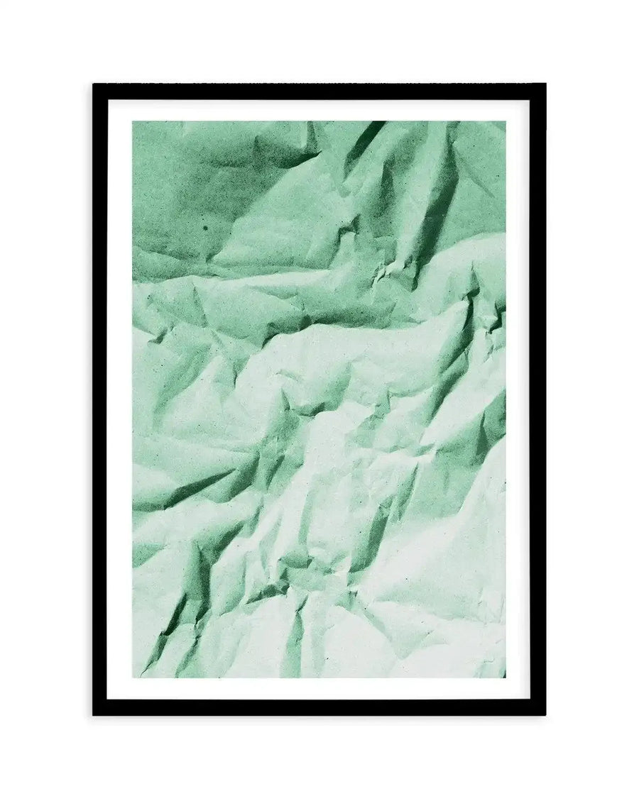 Abstract art print featuring a crumpled paper texture in varying shades of muted sage green and pale mint, creating a dynamic composition of light and shadow, displayed in a black frame with white border.