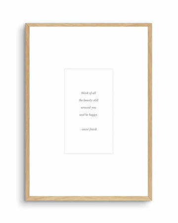 Framed art print with natural wood frame displaying an inspirational quote in gray serif italics centered on white background. The quote reads "think of all the beauty still around you and be happy." attributed to "- anne frank" below. White border surrounds the printed text. Minimalist composition with ample negative space creates a calm, reflective mood suitable for home or office display.