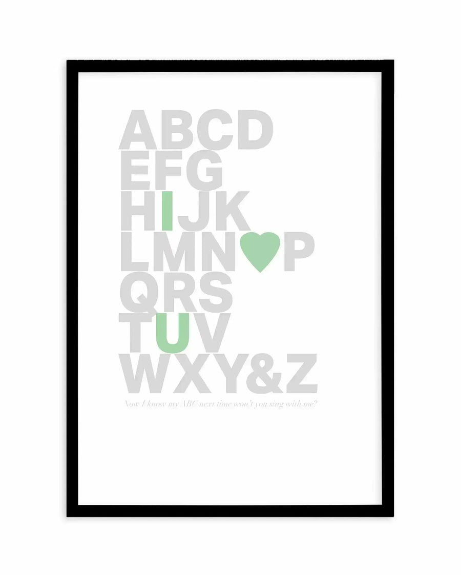 Framed art print with black border displaying the alphabet in large gray capital letters arranged vertically. Five letters are highlighted in sage green: I, O, U, and a heart symbol replacing O. Text at bottom reads "You I know my ABC next time won't you sing with me?" in small gray italics. White background with clean, minimalist design.