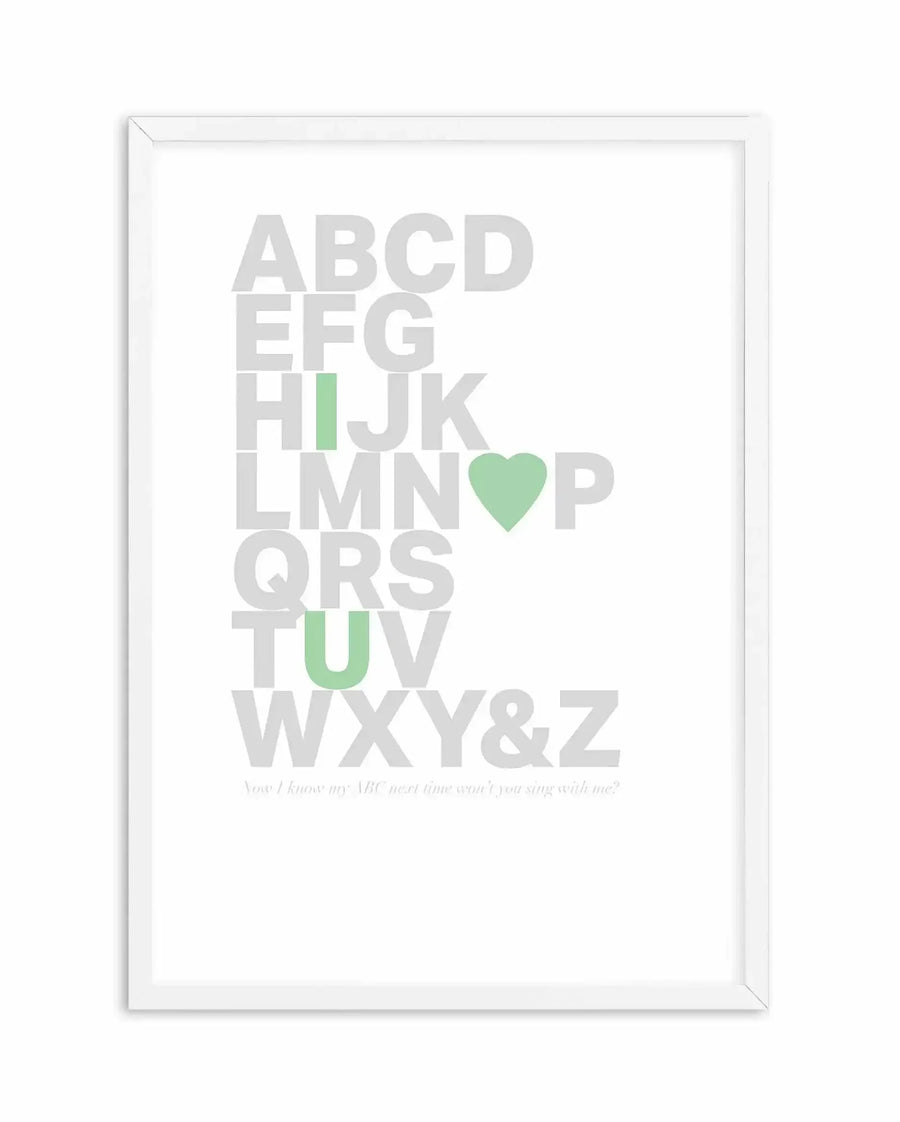 Framed art print featuring the complete alphabet in large, light gray capital letters arranged vertically. The letter "I" is highlighted in sage green, the letter "O" is replaced with a sage green heart shape, and the letter "U" is in sage green. At the bottom, small italicized gray text reads "You I know my ABC next time wont I you sing with me?" The artwork is displayed in a white wooden frame with a white border against a white background.