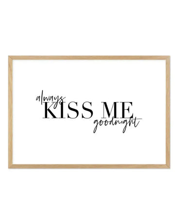 Art print featuring the phrase "always KISS ME goodnight" in a mix of script and serif fonts, printed in black on a white background and displayed in a natural oak frame with white border.