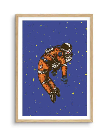 Art print featuring an illustration of an astronaut floating in outer space against a deep blue background with scattered yellow stars. The astronaut wears an orange suit with visible details like straps and buckles, and a dark helmet with a red visor, depicted in a slightly slumped, relaxed posture. The print is displayed in a natural oak frame with a white border.