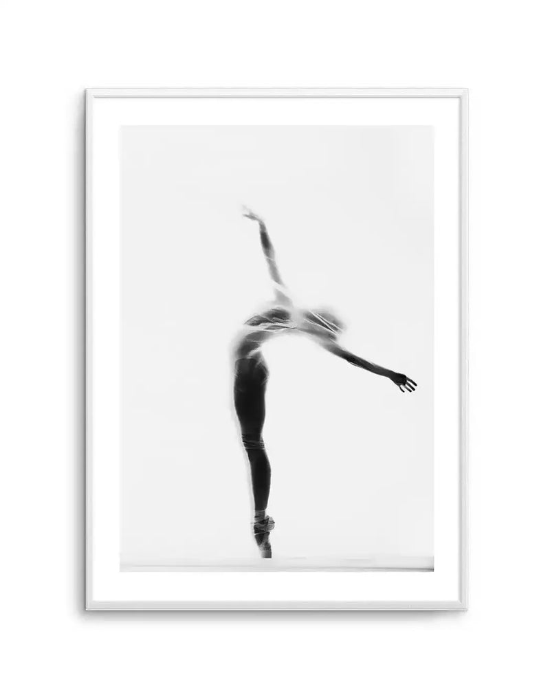Framed black and white photograph of a ballerina en pointe, captured in silhouette behind a translucent fabric. The dancer is posed with her back arched, one arm extended upwards and the other to the side, creating a graceful, ethereal form. The image is printed on fine art paper and displayed in a white frame with a white border.