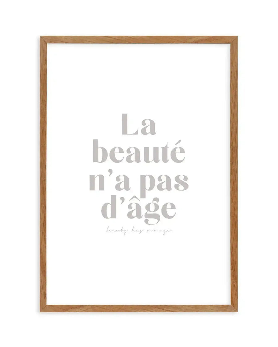 Framed art print with natural wood frame displaying centered gray serif text reading "La beauté n'a pas d'âge" with smaller italicized script below. White background with clean, minimalist design emphasizing the French phrase about beauty and age.