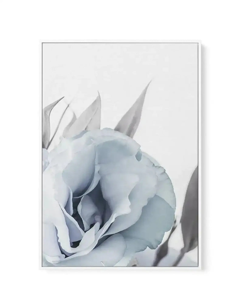 Framed canvas art print of a pale blue lisianthus flower with delicate, layered petals rendered in soft watercolor style. The bloom is shown in close-up detail with subtle gray and blue tones creating depth within the petals. Pointed sepals extend upward from the flower head. The composition is centered on a light gray background. The canvas is mounted in a simple gray frame with a white border, displayed against a neutral backdrop.