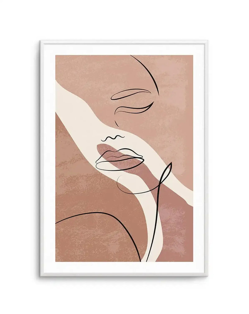 Abstract art print featuring a continuous line drawing of a woman's face with closed eyes and full lips, rendered in black on a background of textured dusty rose and warm beige. The composition includes a wide, curving cream stripe that diagonally crosses the face. The print is displayed in a white frame with a white border.