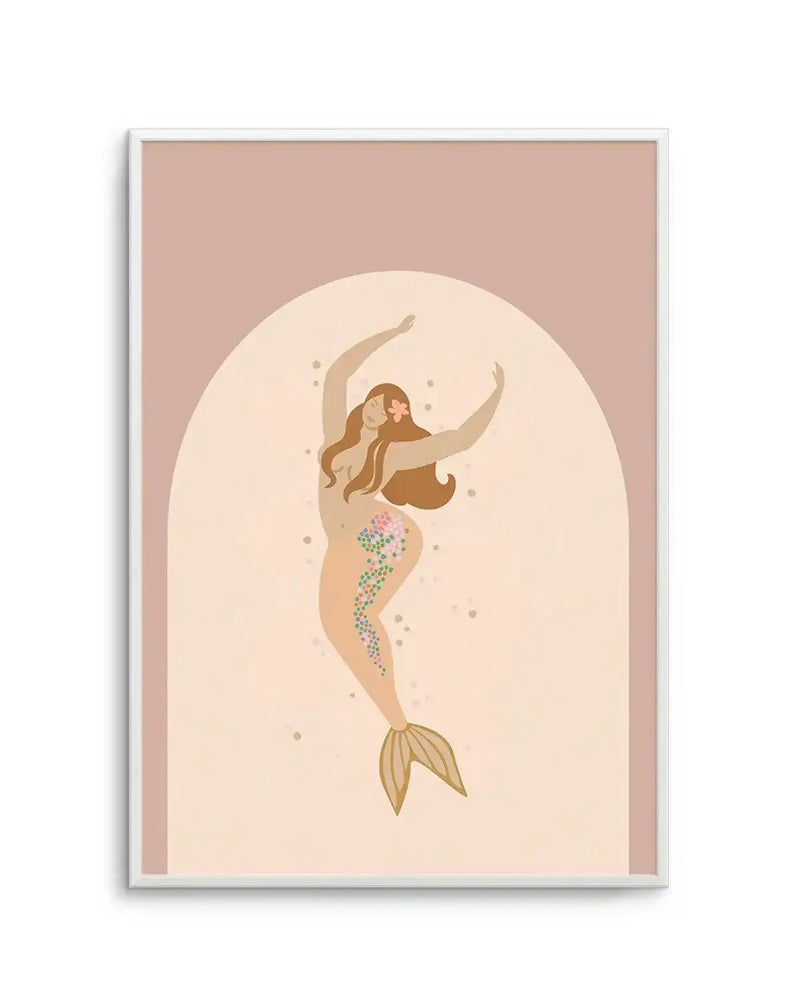 Art print featuring a stylized illustration of a mermaid with warm brown skin and hair, arms raised in a dance pose, against a soft peach background with a lighter arched shape behind her. The mermaid's tail is a light peach with a golden fin, and her hip and tail are adorned with small, colourful floral patterns in pink, green, and blue. The print is displayed in a white frame with a white border.