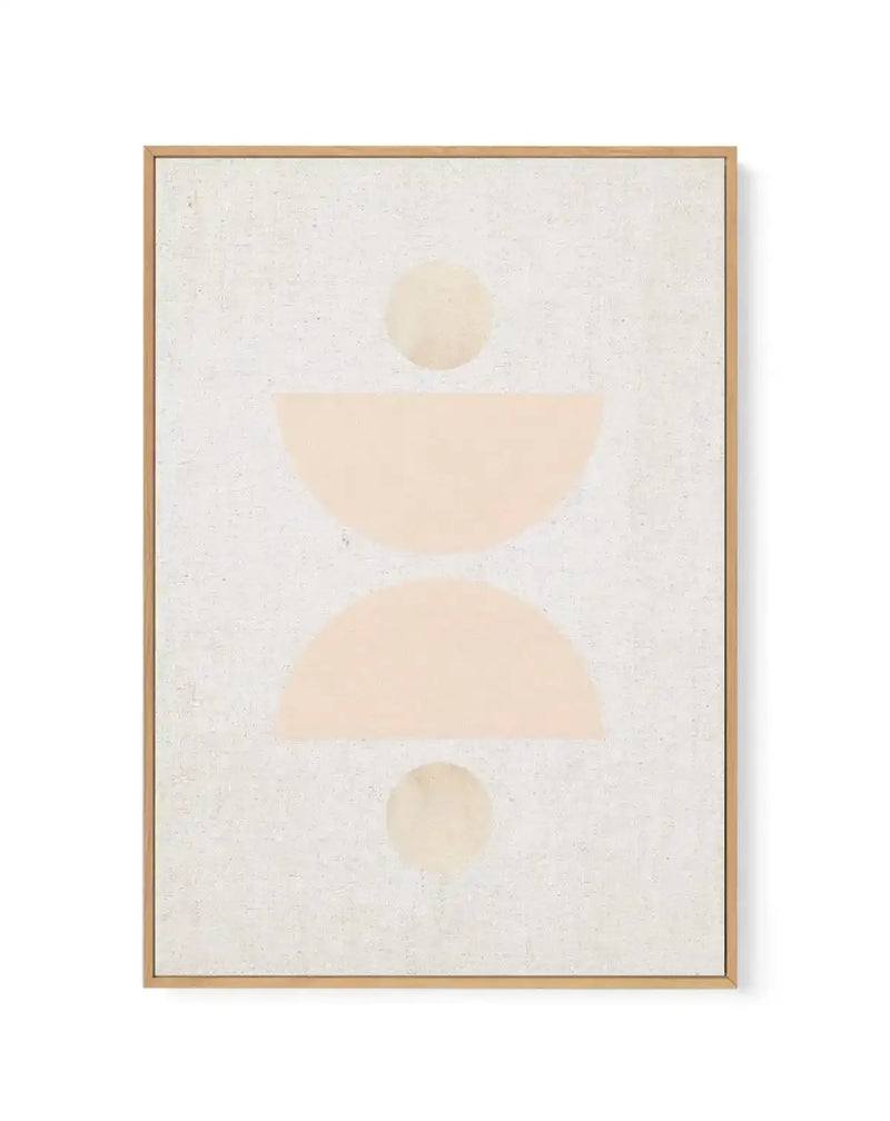 Framed canvas art print featuring an abstract minimalist composition on a cream textured background. The design consists of soft geometric shapes in warm beige and pale peachy tones arranged vertically: a small circle at top, a curved semicircle in the middle, a larger organic shape below, and another small circle at the bottom. The artwork has a matte finish with subtle watercolor-like quality. Natural wood frame with light tan finish and white border surrounding the canvas.