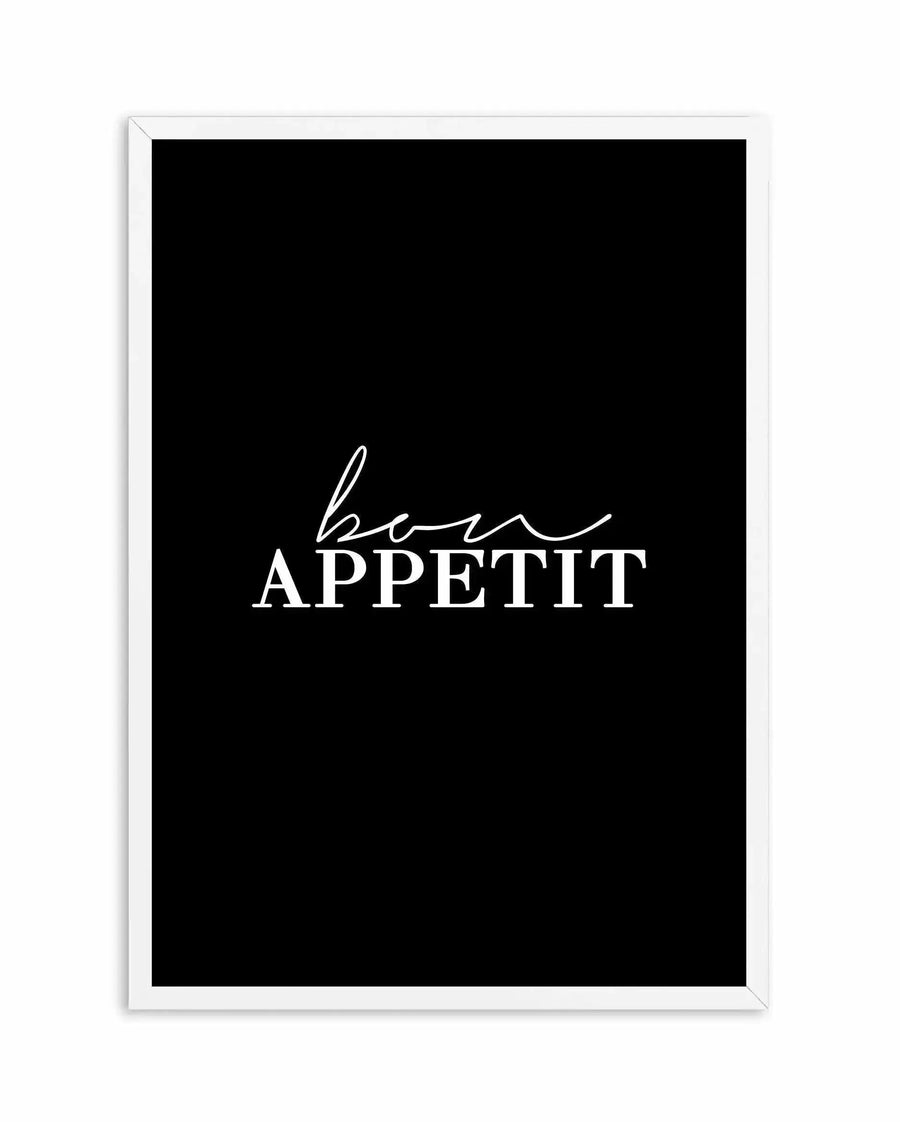 Bon Appetit Art Print displayed in a white frame against a white background. The artwork features a black background with white text reading "bon APPETIT" in a mixed serif and script font style, with "bon" written in a flowing cursive script and "APPETIT" in capital letters with an underline accent.