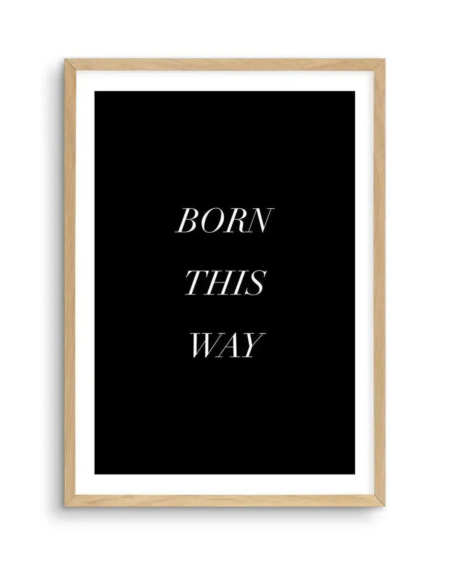 Black art print featuring the words "BORN THIS WAY" in white, sans-serif, italicized font, printed on fine art paper and displayed in a natural oak frame with white border