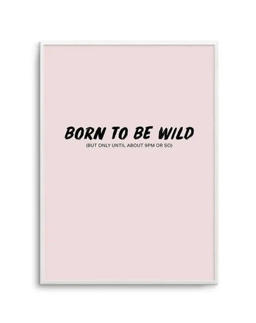 Framed art print on a light pink background featuring black italic text reading "BORN TO BE WILD" with smaller text below stating "(BUT ONLY UNTIL ABOUT 9PM OR SO)". The print is displayed in a silver-toned frame with a white border, centered on the soft blush pink background.