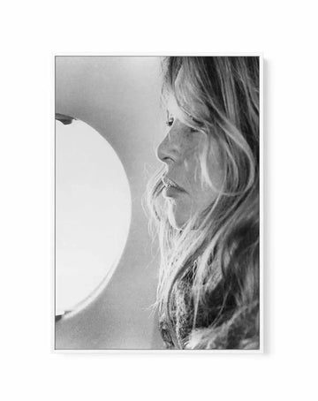 Black and white portrait photograph of a woman with long wavy hair and distinctive facial features, shown in profile facing left. The photograph captures fine details of her face, hair texture, and contemplative expression. The image is printed on canvas with a thin gray frame and white border, displayed against a plain background. The monochromatic photography has a classic, timeless quality with subtle tonal gradations typical of mid-century portrait photography.