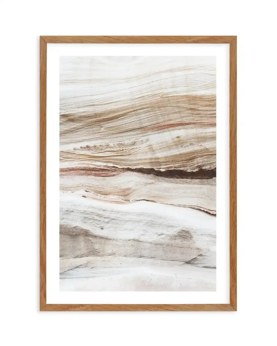 Framed art print titled Bronte Rocks I featuring layered geological rock formations in natural earth tones. The composition shows horizontal strata in cream, tan, brown, and rust hues with subtle texture suggesting sedimentary layers and weathering. The photograph captures the organic, rippling patterns of natural stone surfaces. Presented in a natural wood frame with white border.