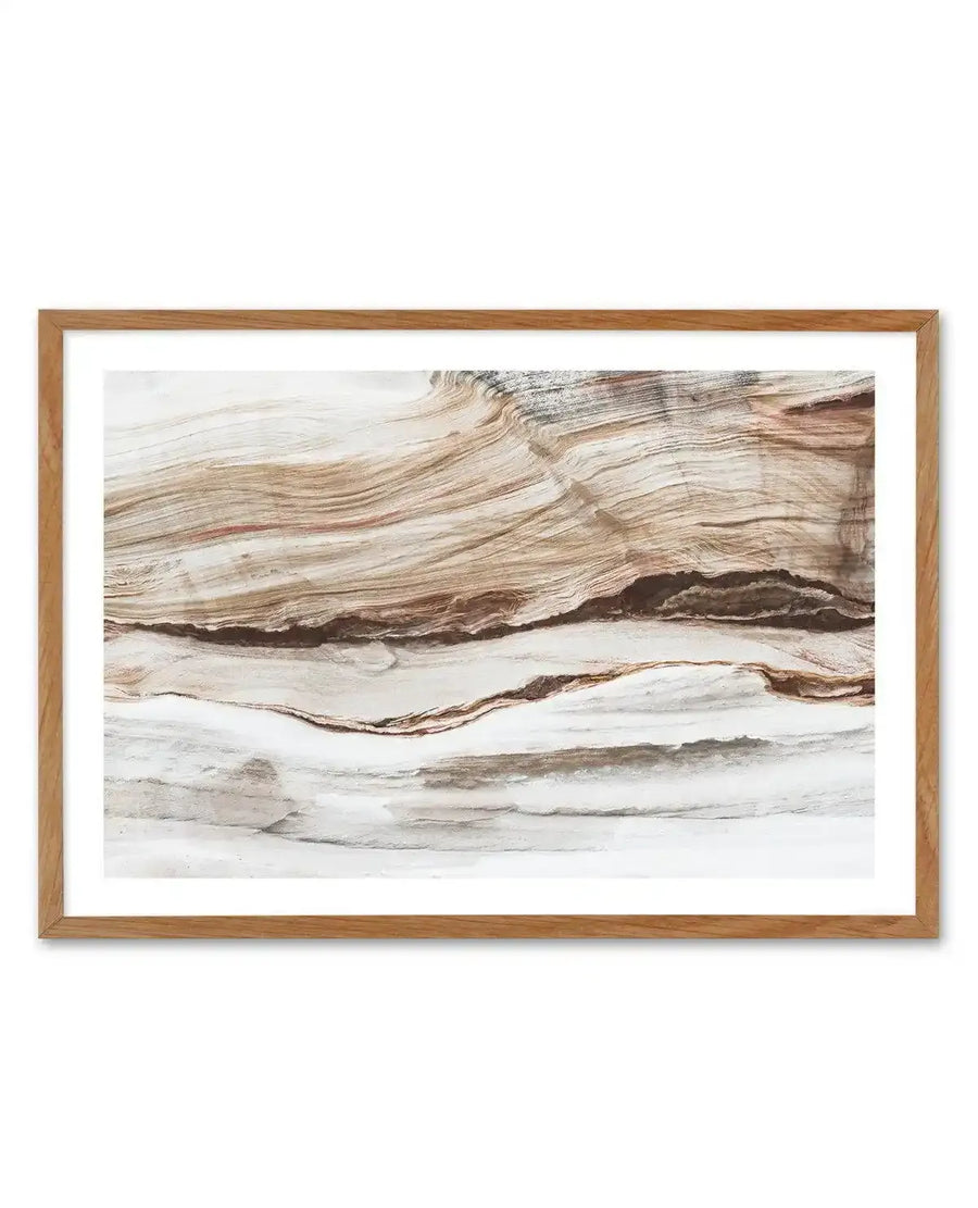 Bronte Rocks art print in natural wood frame with white border, featuring a watercolor landscape of layered rock formations. The composition shows horizontal bands of sedimentary stone in cream, tan, brown, and rust tones with subtle striations and shadowed cavities. The soft, fluid brushwork creates an abstract geological landscape with warm earthy colors and delicate gradations suggesting natural erosion and stratification.