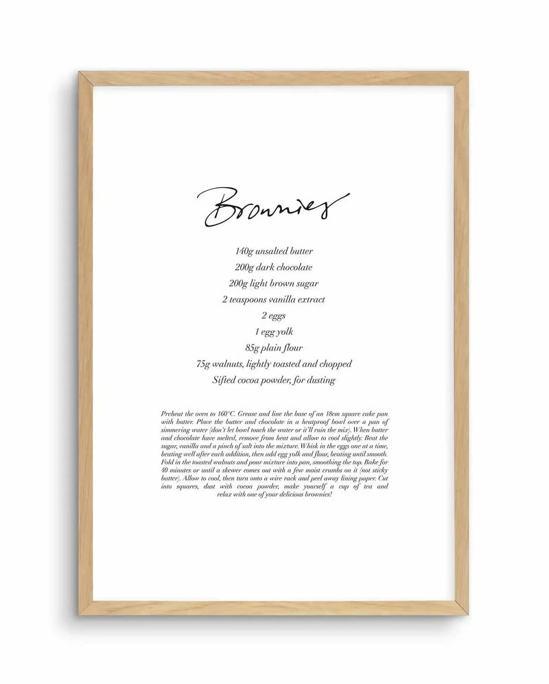 Recipe art print featuring the word "Brownies" in elegant black script at the top, followed by a list of ingredients and baking instructions in a delicate serif font, all on a clean white background, displayed in a natural oak frame with white border.