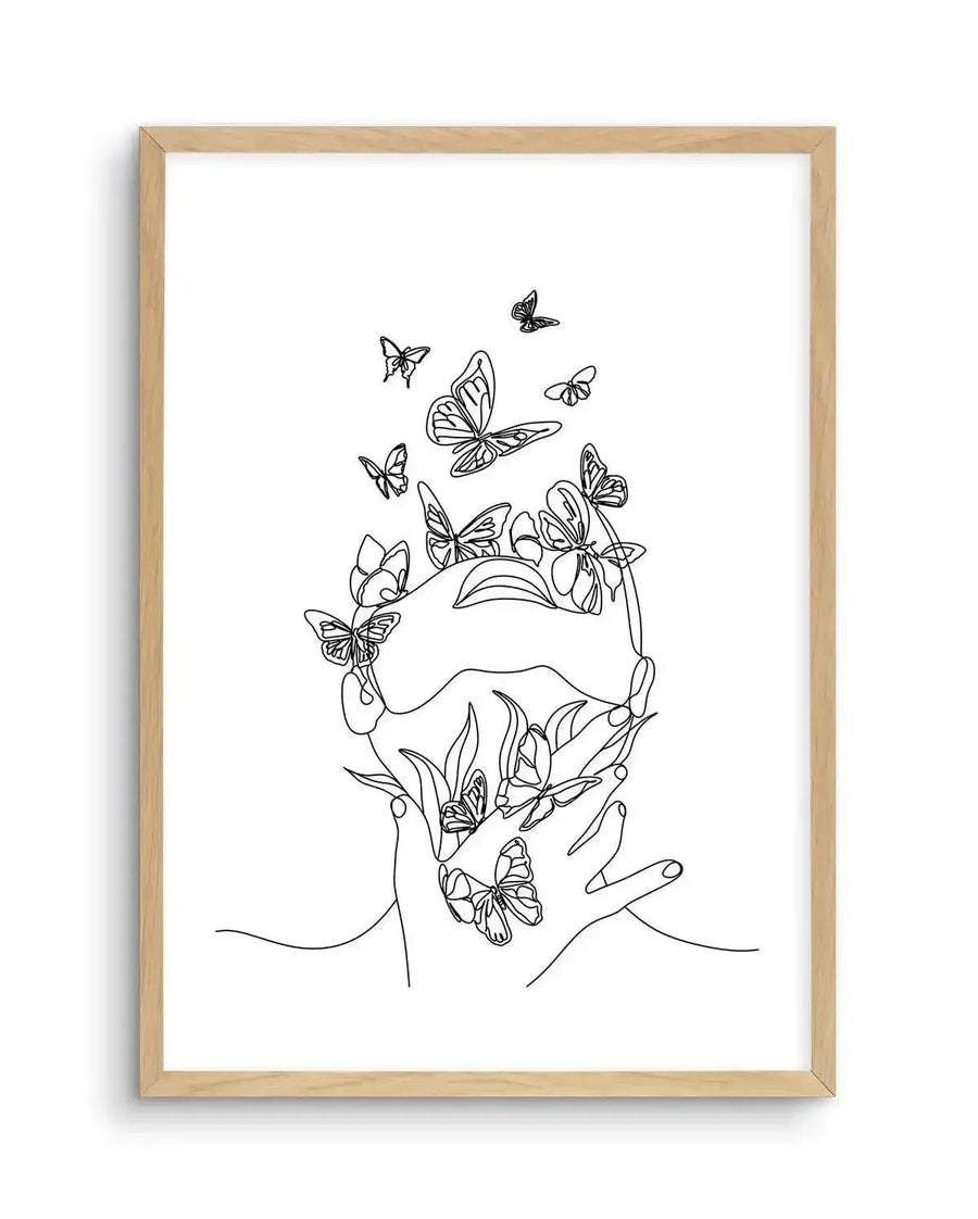 Line art print featuring a continuous black line drawing of a person's face and hands, with numerous butterflies emerging from and surrounding them, on a plain white background, displayed in a natural oak frame with white border.