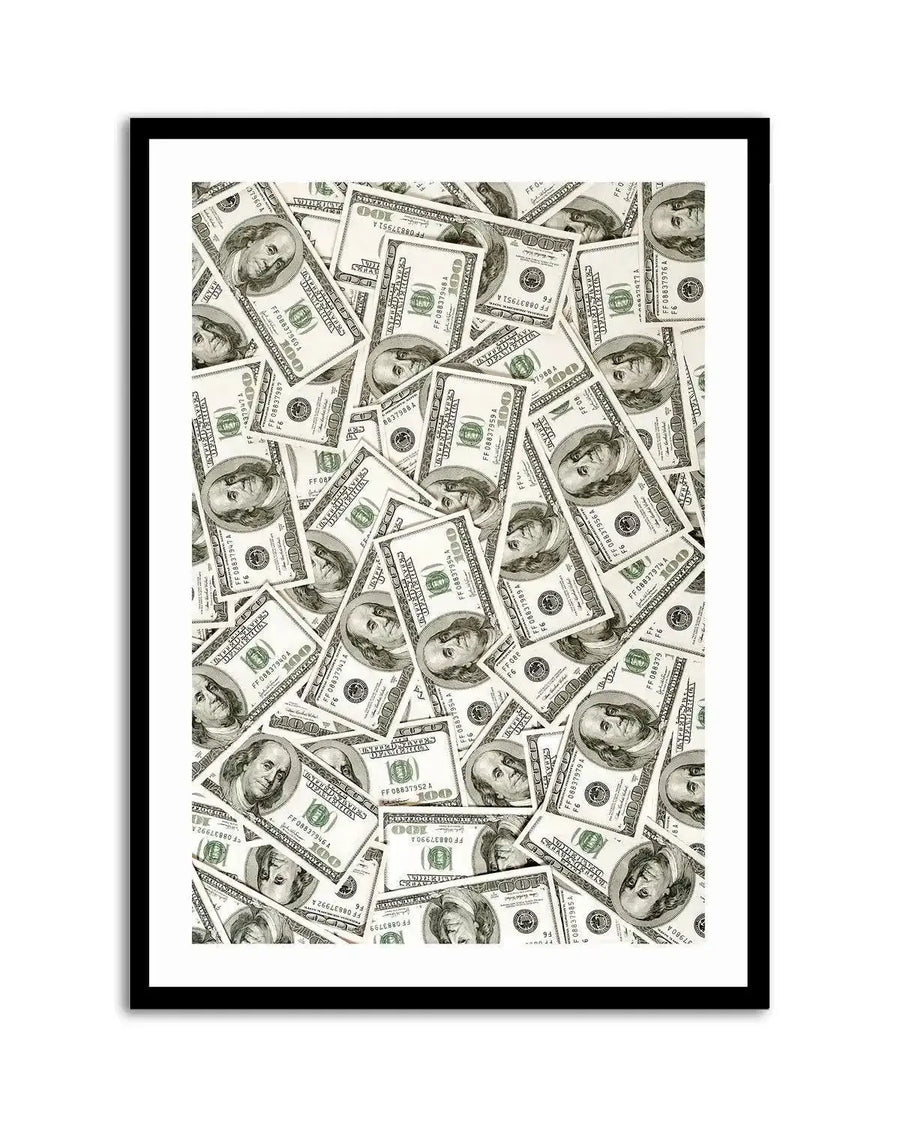 Framed art print featuring a close-up overhead photograph of a scattered pile of US one hundred dollar bills, with a black frame and white border. The bills are mostly face-up, displaying the portrait of Benjamin Franklin, with some bills overlapping and others partially obscured. The composition creates a dense, textured pattern of green, white, and black.