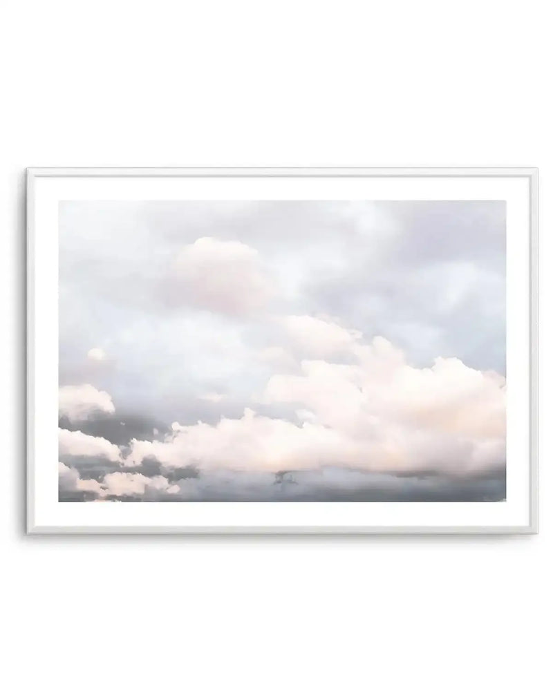 Framed art print featuring a cloudy sky with soft, muted tones. The composition shows layers of clouds in shades of pale grey, white, and subtle hints of blush pink and light blue, creating a serene and ethereal atmosphere, displayed in a white frame with white border.