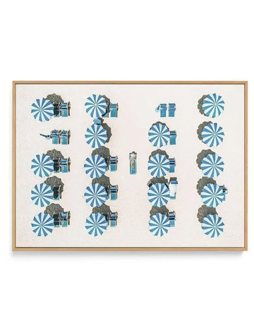 Framed canvas art print featuring an organized grid layout of stylized umbrellas and beach cabins. The design shows repeating blue and white striped umbrellas paired with small illustrated cabins in muted olive and gray tones across four vertical columns. The center features two standalone cabin illustrations. Rendered in a mid-century modern illustration style with a cream colored canvas background. Natural wood frame with white border surrounding the artwork.