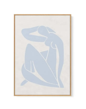 Framed canvas art print featuring an abstract silhouette of a seated female figure in soft periwinkle blue against a cream background. The minimalist design uses flowing, curved lines with white negative space creating geometric shapes within the form. The figure is depicted in a contemplative seated pose with one hand raised. Natural wood frame with light tan finish surrounds the artwork with a white border.