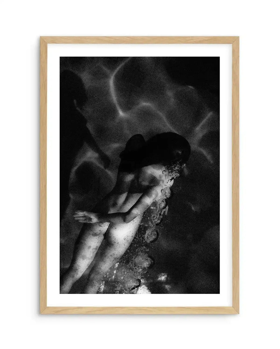 Black and white fine art photograph titled "Deep Soul, Maldives" by Mario Stefanelli, displayed in a natural wood frame with white border. The grainy, high-contrast image depicts a shirtless figure in a cap viewed from above, appearing to float or dive in dark water with ethereal, ghostly forms surrounding them. The composition is vertical, moody, and atmospheric with dramatic lighting that creates an introspective, dreamlike quality.