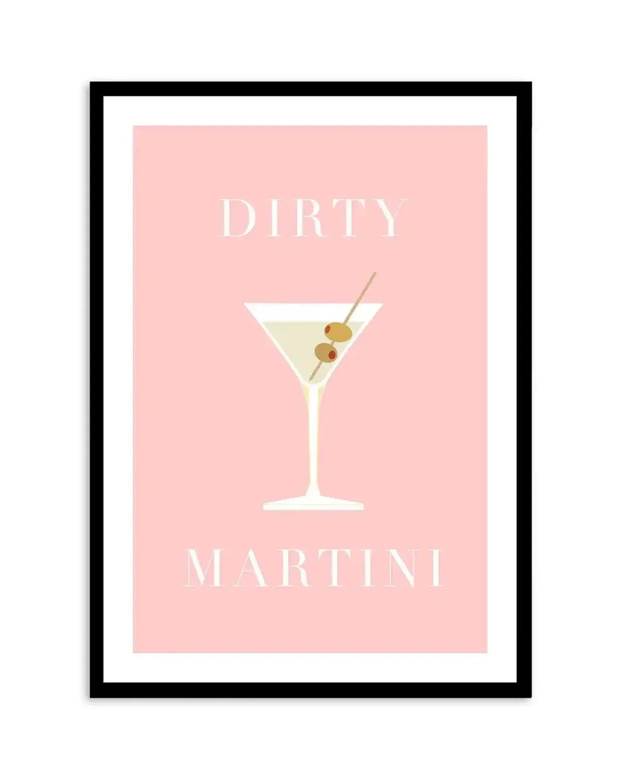Art print featuring a minimalist illustration of a dirty martini cocktail on a soft blush pink background. The martini glass is depicted in white with a pale yellow drink inside, garnished with two green olives and one red pimento on a diagonal pick. The word "DIRTY" is printed in white capital letters above the glass, and "MARTINI" is printed in white capital letters below, both in a classic serif font. The print is displayed in a black frame with a white border.
