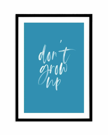 Art print with teal blue background featuring handwritten white text reading "don't grow up" in a casual, flowing script style. The print is displayed in a black frame with white border against a white background.