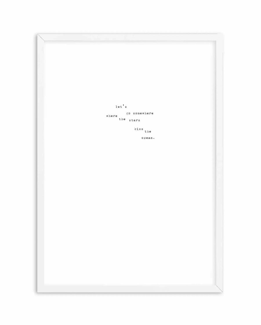 White framed art print featuring typewriter-style text arranged in a scattered, poetic layout. The text reads "let's go somewhere where the stars kiss the ocean." in small, monospaced font on a white background. The words are positioned irregularly across the center of the page, creating a dreamy, wanderlust-inspired composition. Simple white frame with clean lines.