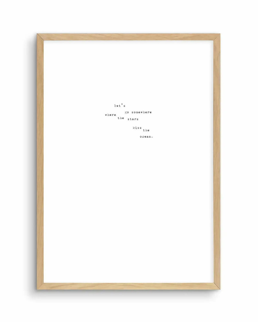 Art print in natural wood frame featuring minimalist typewriter-style text centered on white background. Text reads "let's go somewhere where the stars kiss the ocean." arranged in scattered, descending lines. Simple, monochromatic design with black text on white paper, evoking a dreamy, romantic aesthetic reminiscent of vintage typewritten poetry.