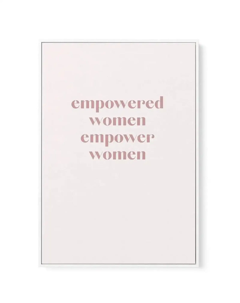 Framed canvas art print featuring the text "empowered women empower women" in dusty rose serif lettering centered on a cream background. The canvas is surrounded by a thin gray frame with a white border. Minimalist design with clean typography on neutral, slightly textured canvas surface.