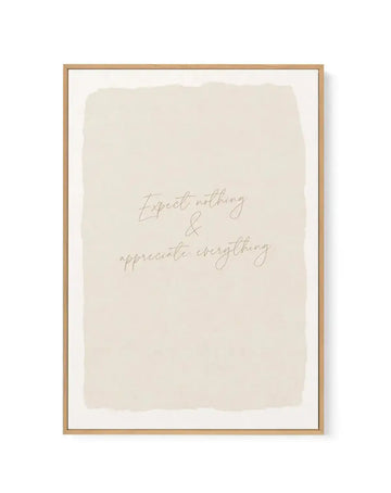 Framed canvas art print with natural wood frame displaying handwritten script text reading "Expect nothing & appreciate everything" in taupe lettering on a soft cream background with organic, watercolor-like wash effect. White border surrounds the canvas within the frame.
