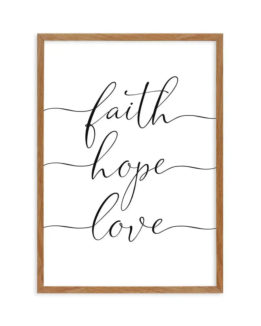 Framed art print with natural wood frame displaying elegant black script calligraphy on white background. Three words are stacked vertically with decorative horizontal lines extending from each: "faith" at top, "hope" in middle, and "love" at bottom. The minimalist design features flowing, connected letterforms in a delicate cursive style against the clean white surface.