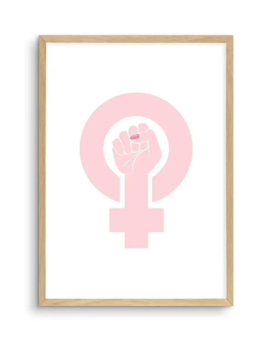 Art print featuring a pale pink female gender symbol with a raised fist in the center, also in pale pink, with a single bright pink fingernail on the index finger, displayed in a natural oak frame with a white border.