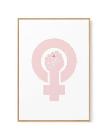 Framed canvas art print featuring a feminist symbol in soft blush pink against a white background. The design shows a female gender symbol with a raised fist integrated into the circle at the top. The artwork is displayed in a natural wood frame with clean lines and a white border around the canvas.