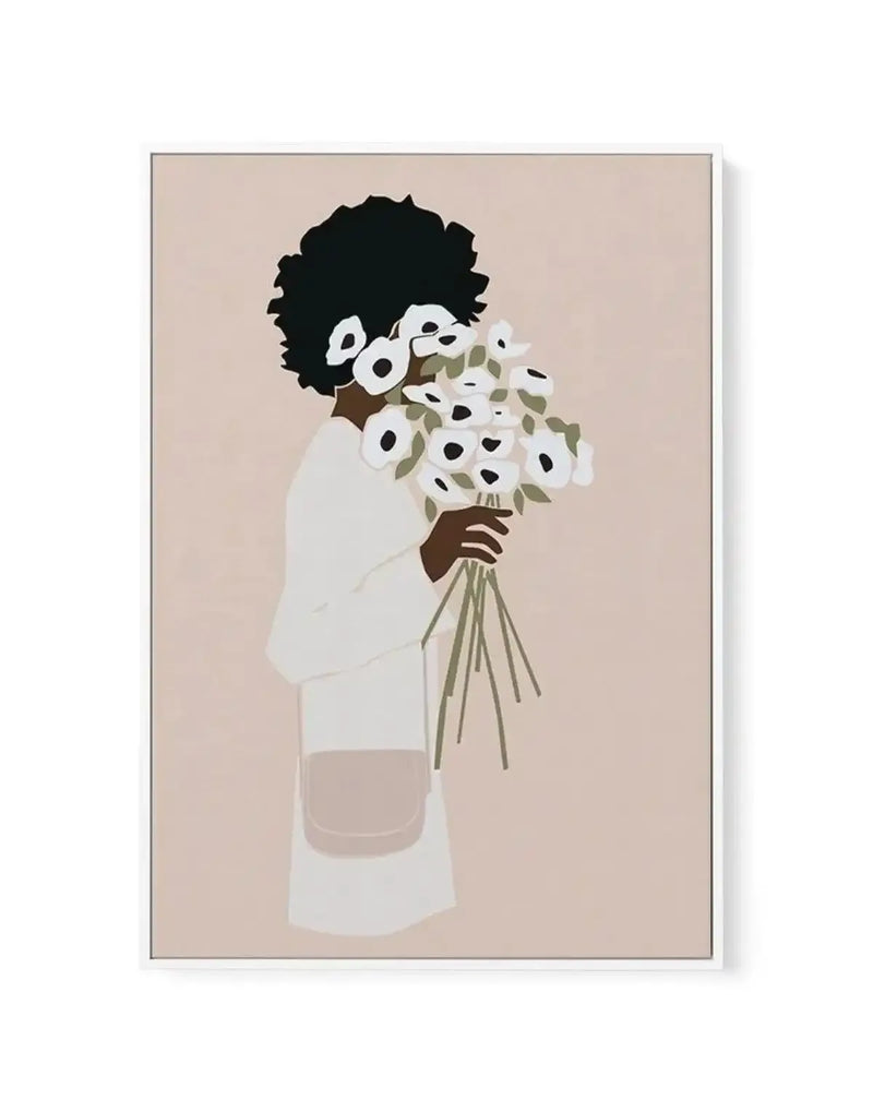 Framed canvas art print featuring an illustration of a woman with a voluminous black afro hairstyle, wearing a cream-colored long-sleeved garment, holding a generous bouquet of white flowers with black centers and sage green stems and leaves. The figure is shown from shoulders up against a warm beige background. The illustration uses a flat, minimalist style with muted earth tones including cream, brown, olive, and taupe. The canvas is mounted in a simple gray frame with a white border.