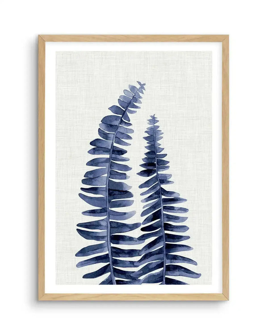 Watercolour art print featuring two tall fern fronds in deep navy blue with visible brushstroke texture on a textured cream background, displayed in a natural oak frame with white border.