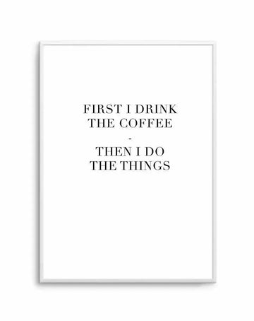 Framed art print with white border featuring black serif typography centered on a white background. Text reads "FIRST I DRINK THE COFFEE - THEN I DO THE THINGS" arranged in four lines. The print is housed in a silver-toned frame with a subtle shadow effect visible against a light background.