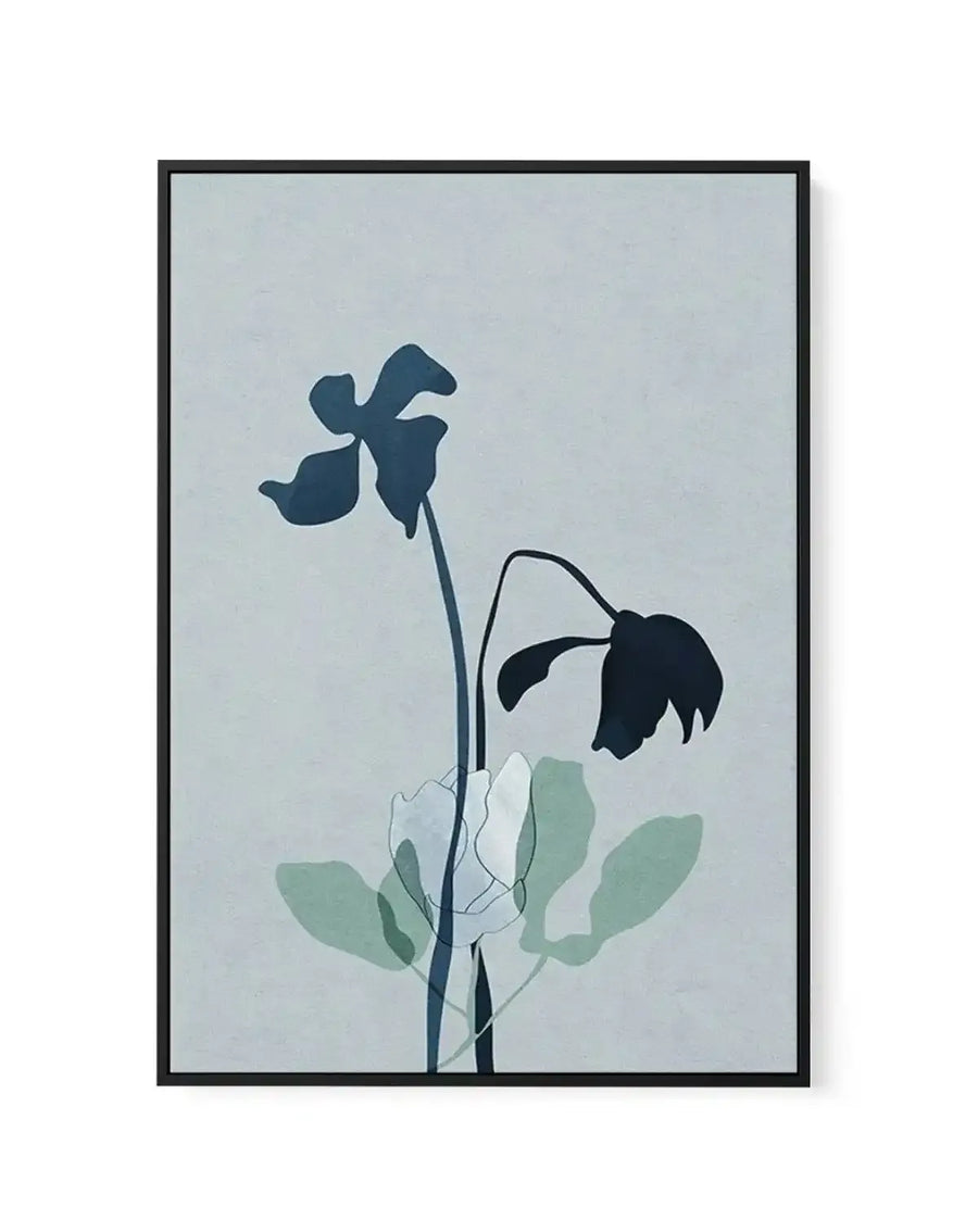 Framed canvas art print featuring minimalist botanical illustration with two flowering stems against a soft gray-blue background. Upper stem displays a dark teal silhouetted bloom in full flower. Lower stem shows a drooping dark navy flower past its peak. Soft sage green watercolor-style leaves accent the composition. Black frame with white border completes the piece.