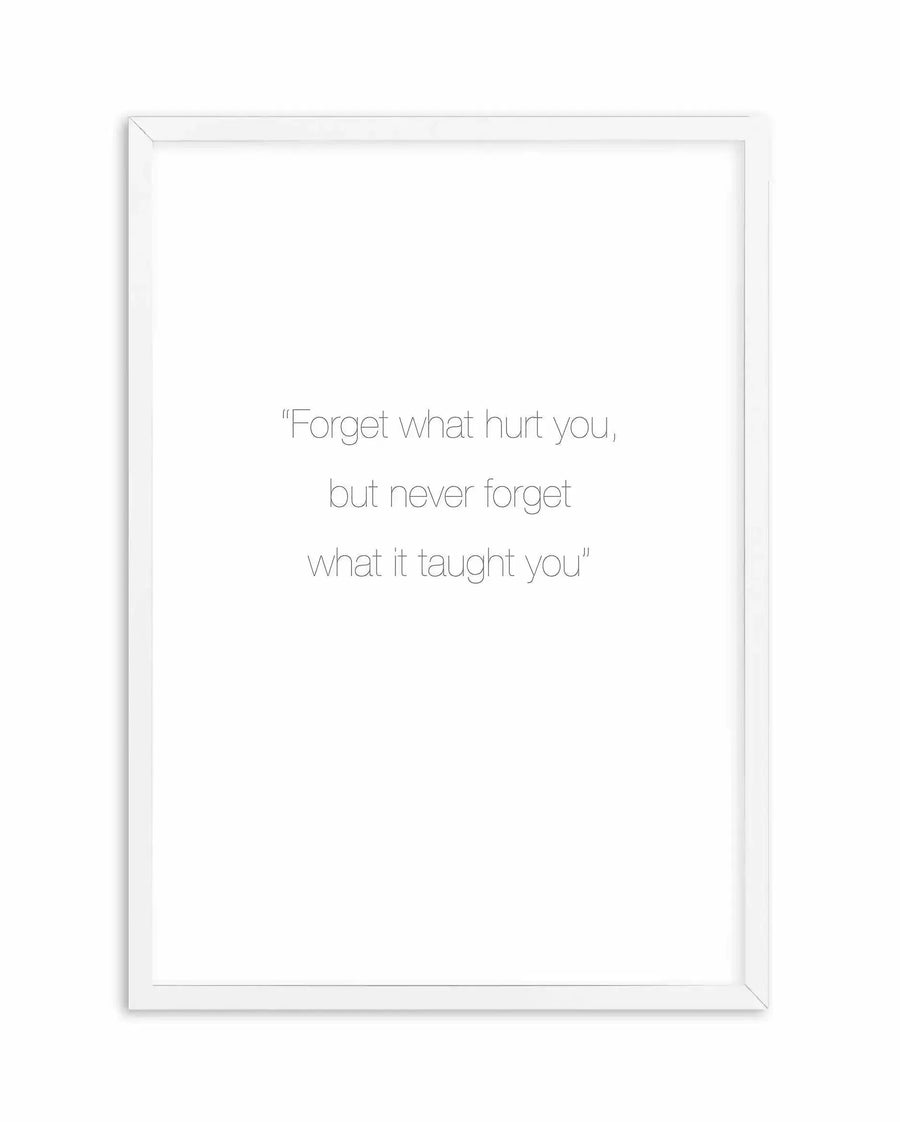 Framed art print with white border featuring an inspirational quote in light gray sans-serif typeface centered on a white background. The quote reads "Forget what hurt you, but never forget what it taught you" in three centered lines. The print is displayed in a simple white wooden frame with visible depth and dimension, shown against a plain white background.