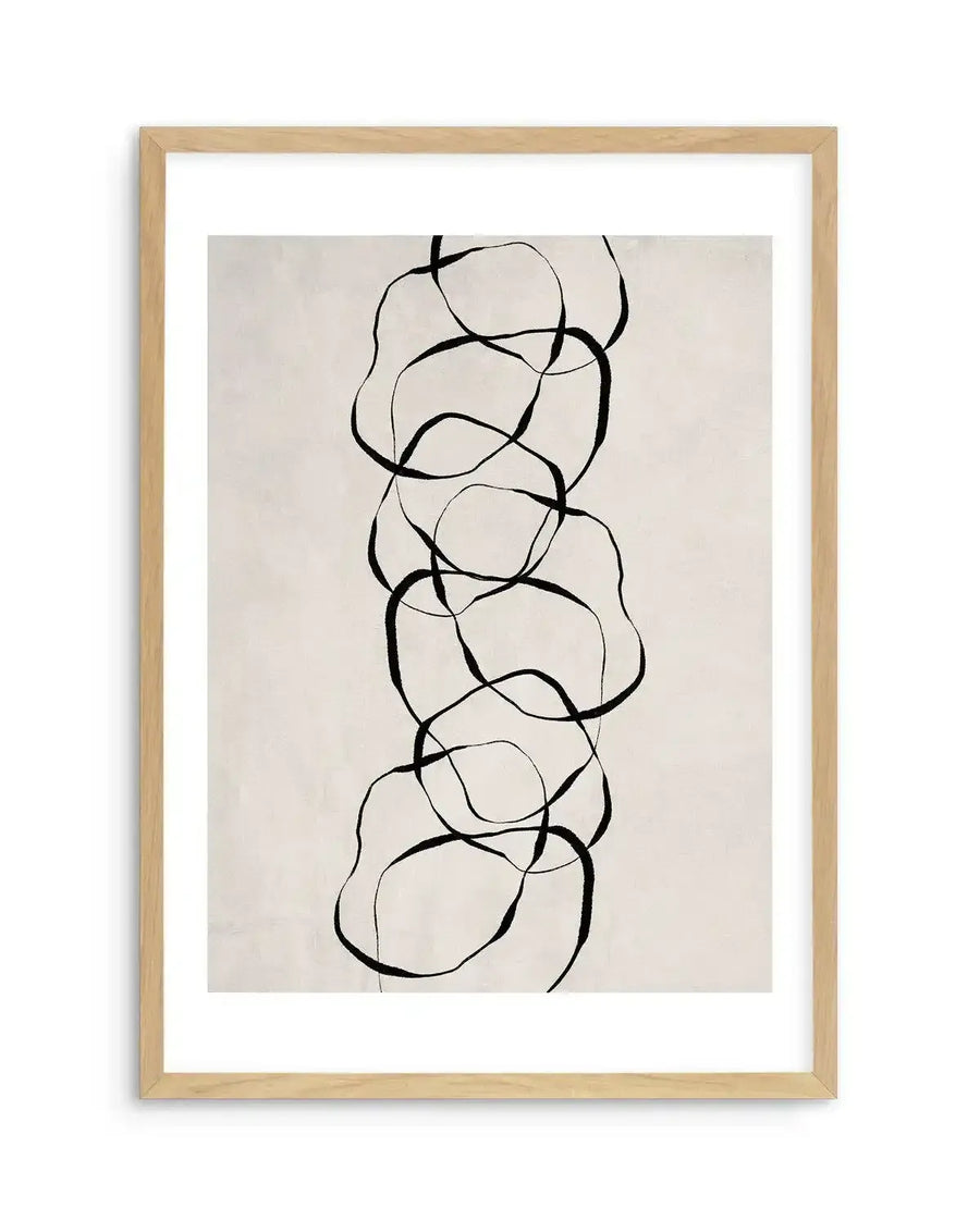 Framed art print featuring an abstract line drawing in black ink on a cream background. The composition shows a vertical arrangement of overlapping organic shapes resembling rounded forms or cells, connected by flowing curved lines. The thin to medium-weight black lines create a continuous, gestural pattern down the center of the composition. The artwork is mounted in a natural wood frame with a white border.